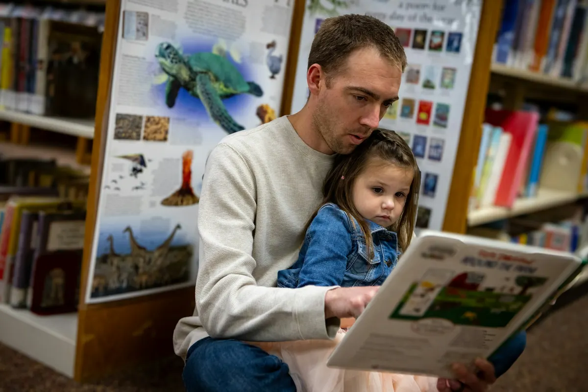 Adult reading a picture book with a young child